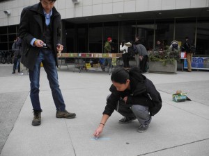 Jessica Tong and Alex Lu write powerful messages in chalk outside the UCC. Photo by Andrea Smith.